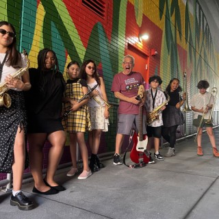 A group photo of kids and a teacher holding various instruments