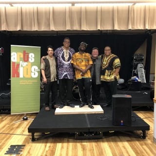 a group poses on a stage in front of an Art For Kids banner