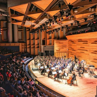 A symphony orchestra performing onstage in a large auditorium