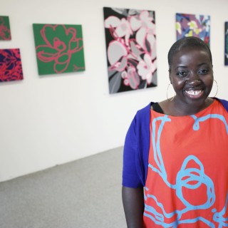 An artist smiles in front of her artwork