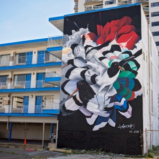 a mural of black and white birds on the side of a beachfront motel