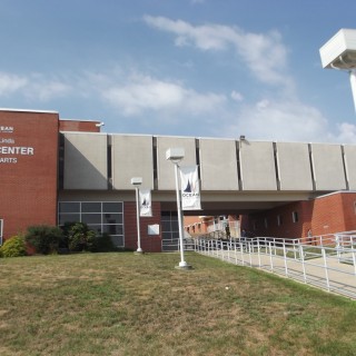 the exterior of the Jay and Linda Grunin Center for the Arts, a brown and white building with a long sidewalk walkway