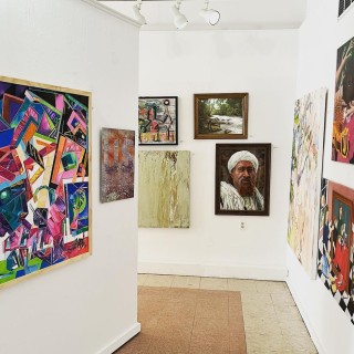 various artworks hung on art gallery walls, a mix of portraits, landscape, abstract, and other art styles