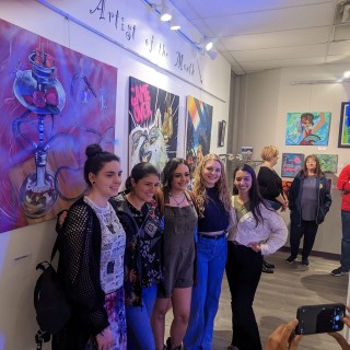 a group takes a photo in front of the art at a gallery opening