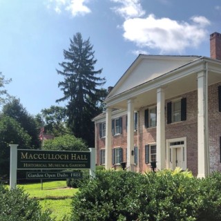 Exterior of Macculloch Hall, a brick building with columns surrounded by foliage
