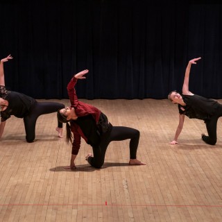 three dancers wearing all black rehearse a dance move