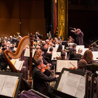 A conductor leading an orchestra on stage