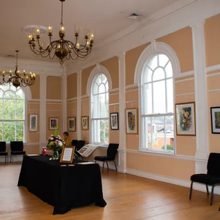 an interior image of the Lyceum Hall Center for the Arts with arched windows and a table in the center of the room