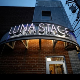 the Luna Stage sign lit up in front of a modern brick building