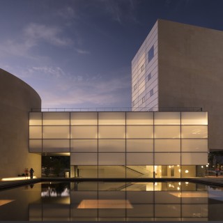 Twilight image of multi-building complex across a pool of water