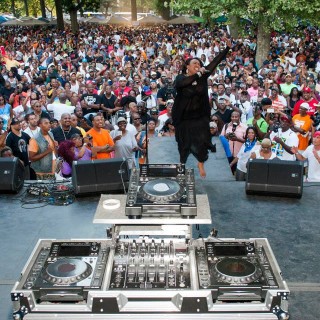 a performer singing in front of a large crowd at an outdoor music festival, the Lincoln Park Music Festival