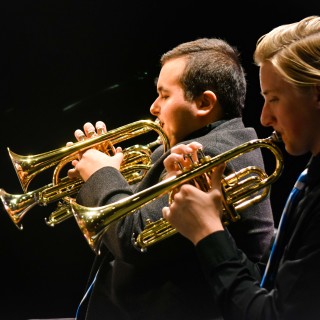 Two men playing trumpets at a concert.