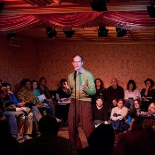 A man is standing in front of a crowd of people talking into a microphone