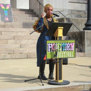 Woman speaking at podium during a poetry festival.