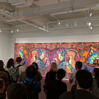 A group of people standing in front of a large colorful piece of art