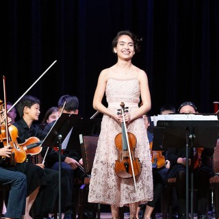 A female violinist standing in front of an orchestra