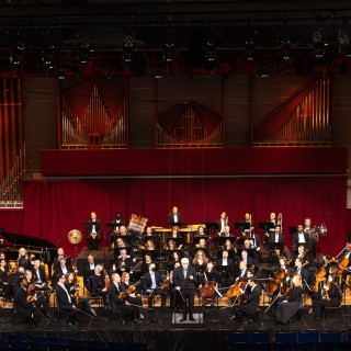 Orchestra performing before a pipe organ.