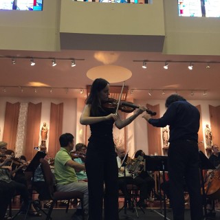 A woman play ing a violin in a church.