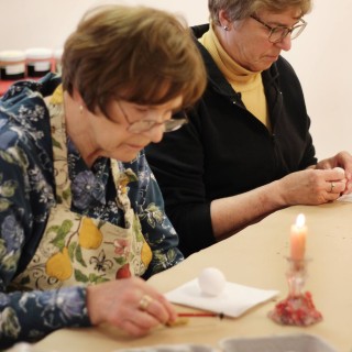 Two women painting eggs.