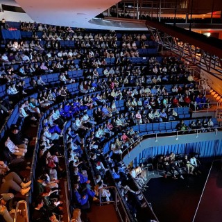 A large auditorium with many people in the seats.
