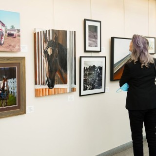 a woman standing in front of an art gallery wall.