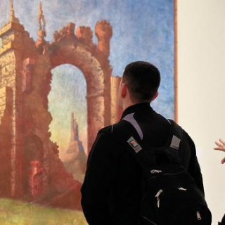 Spectators in art gallery viewing artwork on the walls.