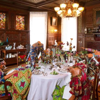 Elaborate table setting with mannequins sitting around dressed in period garb made of African inspired print.