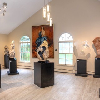 Hand carved stone sculpture and paintings fill a large room with arched windows in the Skylands Museum of Art.
