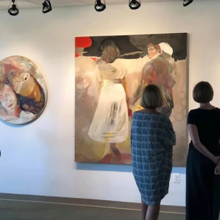 A group of people looking at paintings in an art gallery.