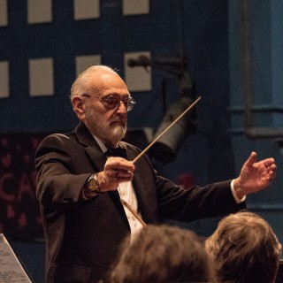 A man in a tuxedo conducting an orchestra