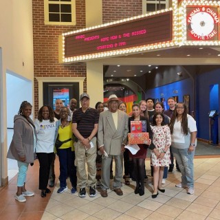 A group of people in front of a theater marquee