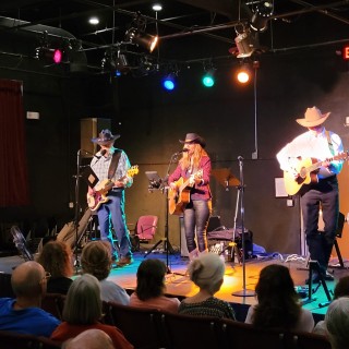 A group of people wearing cowboy hats playing music in a music venue.
