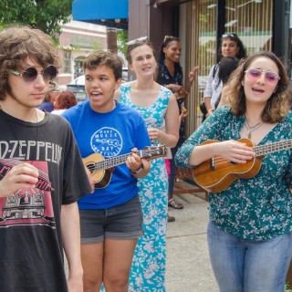 People sing and play ukuleles on the sidewalk for Make Music Day in Montclair NJ