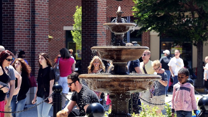 People gathered around a plaza with a fountain in the middle in Collongswood