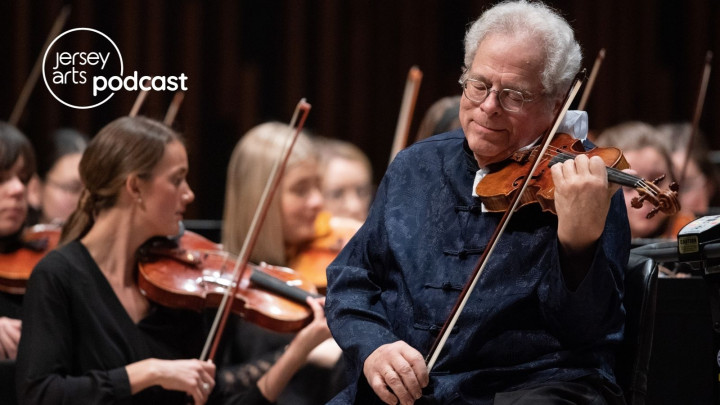 Itzhak Perlman standing, playing the violin, with violinists behind him sitting in chairs
