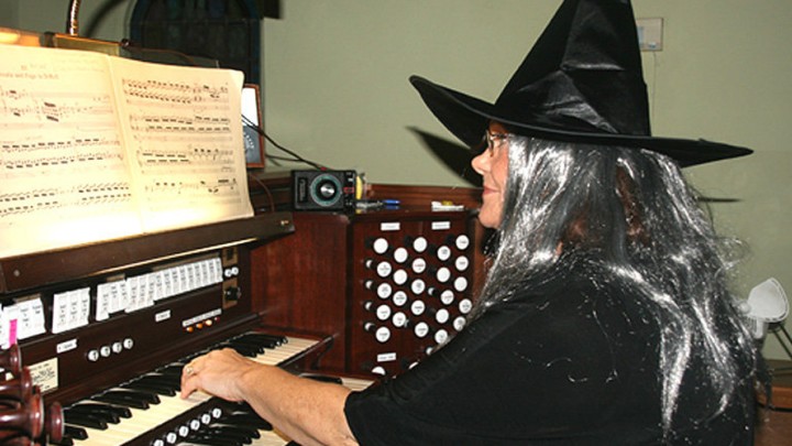 A woman dressed as a witch playing the piano