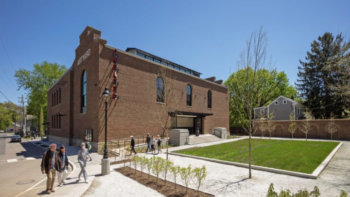 the outside of the ArtYard building, a church-like brown brick building arched windows and a neat square of grass out front