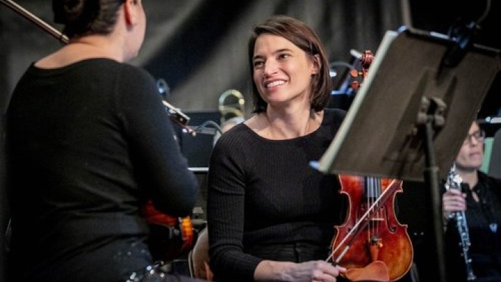 two female musicians holding violins take a break to talk between songs