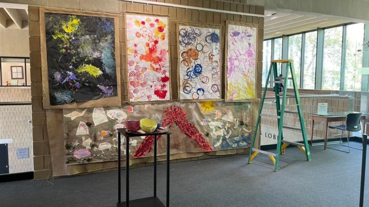 Four colorful abstract paintings hung up on the walls of an art gallery