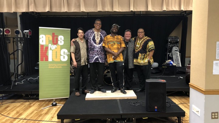 a group poses on a stage in front of an Art For Kids banner