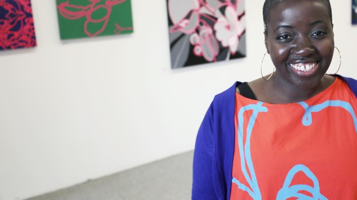 An artist smiles in front of her artwork