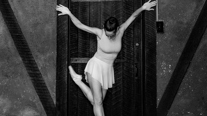 A ballerina from Allegory Dance in front of a wooden door. Photo by Impressions.Life Jeff Somers