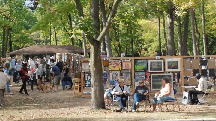 wooden art display grids of paintings set up in the woods for people to browse and shop