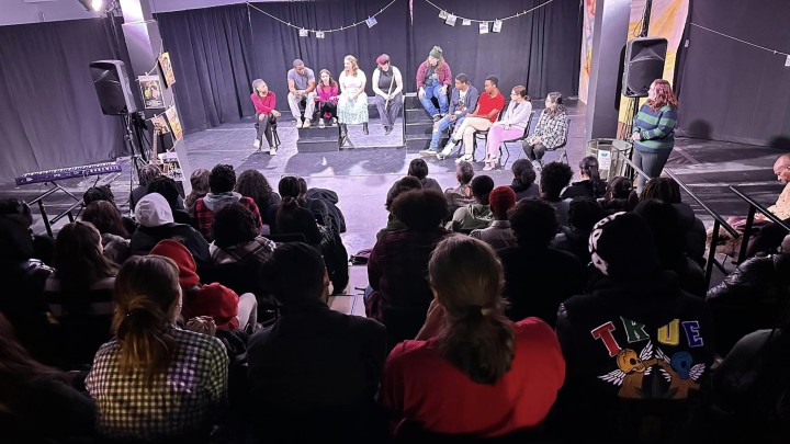 A group of actors on stage speaking to audience memebrs