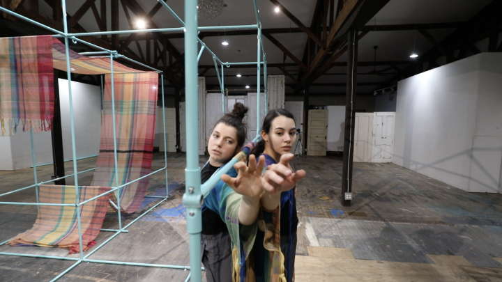 Dancers performing amongst a scaffolding set.