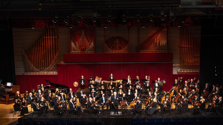 Orchestra performing before a pipe organ.