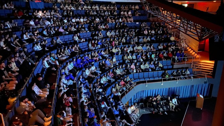 A large auditorium with many people in the seats.