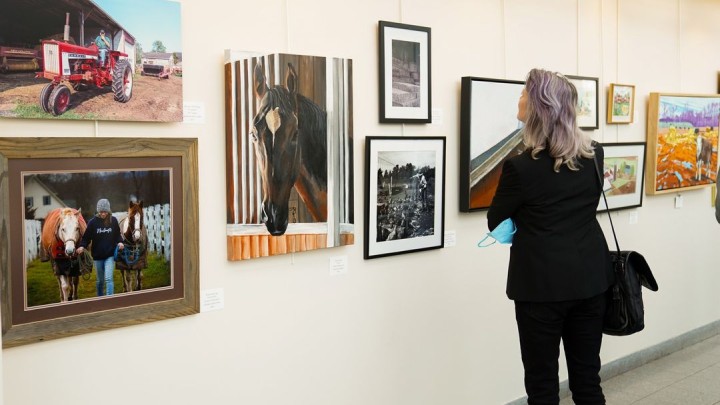 a woman standing in front of an art gallery wall.
