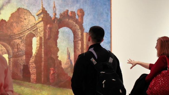 Spectators in art gallery viewing artwork on the walls.