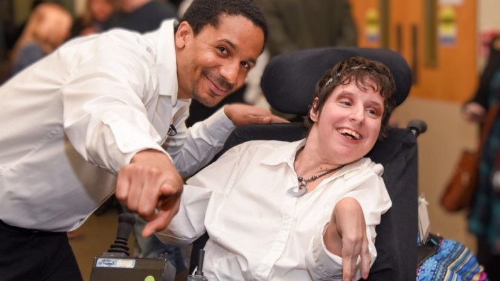 An abled bodied and a person with a disability pose for a photograph.